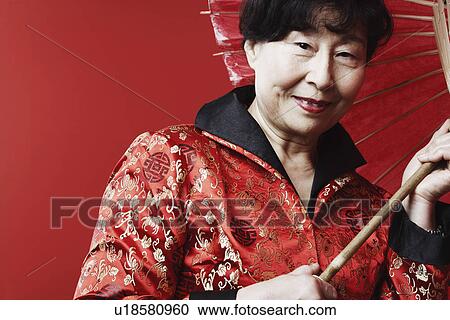 Stock Image - Portrait of a mature woman holding a parasol. Fotosearch