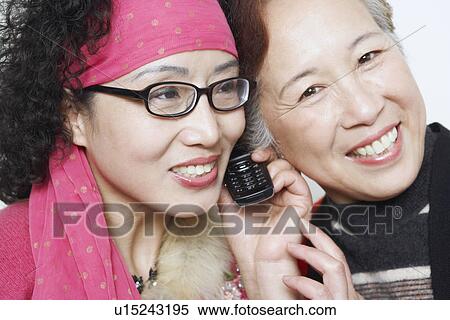 Portrait of a mature woman with her friends using a mobile phone View Large Photo Image Stock Photography - Portrait of a mature woman with her friends using a mobile phone. Fotosearch