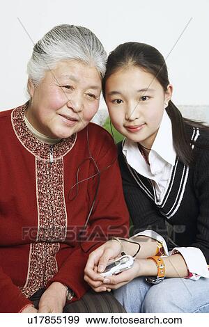 Portrait of a young woman sharing headphones with her grandmother View Large Photo Image Stock Photo - Portrait of a young woman sharing headphones with her grandmother. Fotosearch