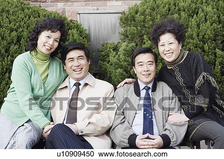 Stock Image - Portrait of two mature couples sitting together smiling. Fotosearch