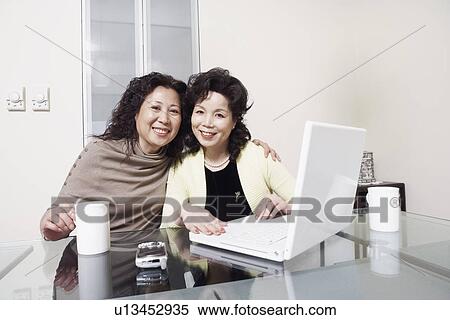 Stock Photography - Portrait of two mature women using a laptop smiling. Fotosearch