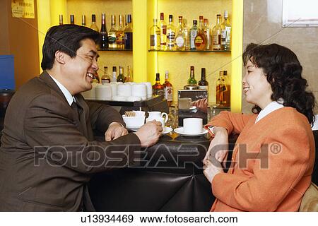 Side profile of a businessman and a businesswoman sitting at a bar counter View Large Photo Image Stock Photo - Side profile of a businessman and a businesswoman sitting at a bar counter. Fotosearch