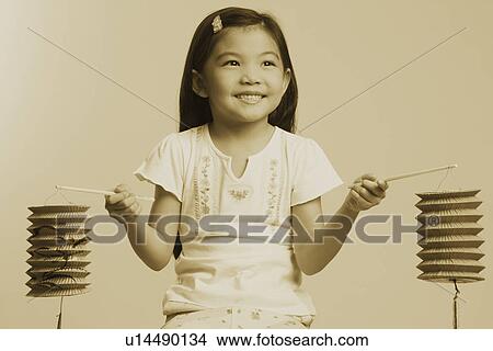 Picture - Close-up of a girl holding two Chinese lanterns and smiling. Fotosearch