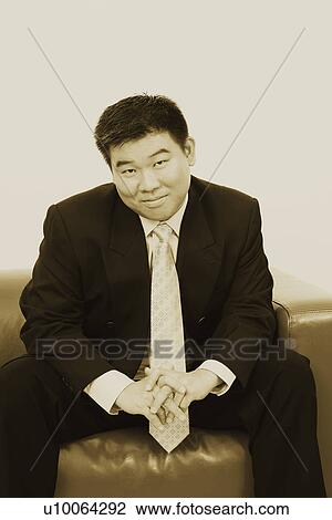 Stock Image - Portrait of a businessman sitting on a couch. Fotosearch