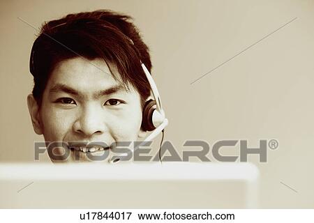 Portrait of a male customer service representative talking on a headset and smiling View Large Photo Image Stock Photo - Portrait of a male customer service representative talking on a headset and smiling. Fotosearch