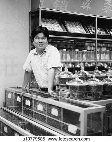Stock Photography - Portrait of a shopkeeper standing at the checkout counter. Fotosearch
