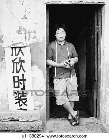 Picture - Portrait of a young man leaning against a door. Fotosearch