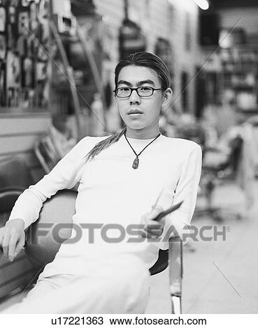 Stock Image - Portrait of a young man sitting on a chair. Fotosearch