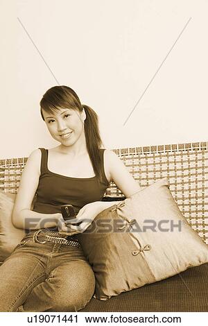 Stock Image - Portrait of a young woman holding a mobile phone and smiling. Fotosearch