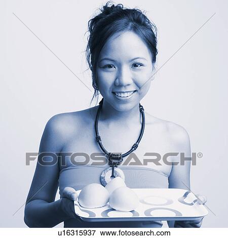 Stock Photo - Portrait of a young woman holding a serving tray and smiling. Fotosearch