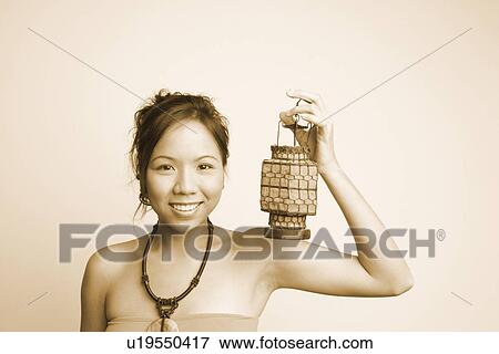 Portrait of a young woman holding a lantern and smiling View Large Photo Image Stock Photo - Portrait of a young woman holding a lantern and smiling. Fotosearch