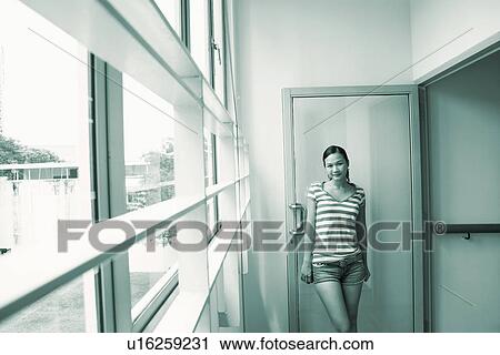 Portrait of a young woman leaning against a door and smiling View Large Photo Image Stock Image - Portrait of a young woman leaning against a door and smiling. Fotosearch