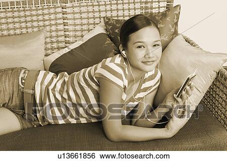 Portrait of a young woman listening to an MP3 player View Large Photo Image Stock Photograph - Portrait of a young woman listening to an MP3 player. Fotosearch