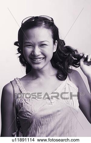 Picture - Portrait of a young woman with her hand in hair and smiling. Fotosearch