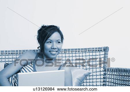 Young woman lying on a couch with a laptop View Large Photo Image Picture - Young woman lying on a couch with a laptop. Fotosearch