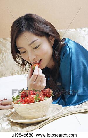 Stock Image - Close-up of a young woman eating strawberries. Fotosearch