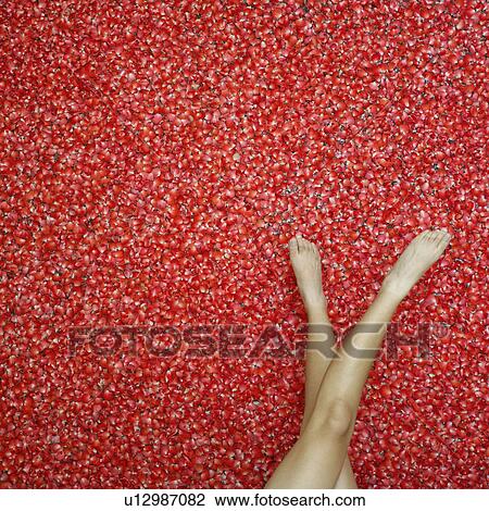 Stock Image - Low section view of a woman on rose petals. Fotosearch