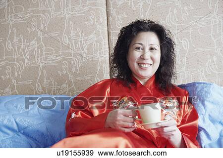 Portrait of a mature woman lying on the bed with a cup of tea View Large Photo Image Stock Photo - Portrait of a mature woman lying on the bed with a cup of tea. Fotosearch
