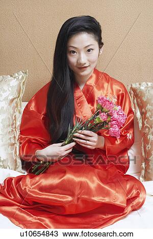 Portrait of a young woman holding a bunch of flowers View Large Photo Image Stock Image - Portrait of a young woman holding a bunch of flowers. Fotosearch