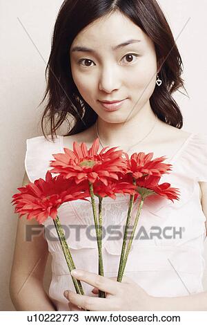 Portrait of a young woman holding flowers View Large Photo Image Stock Image - Portrait of a young woman holding flowers. Fotosearch