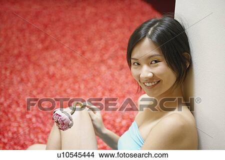 Picture - Portrait of a young woman leaning against a wall and smiling. Fotosearch