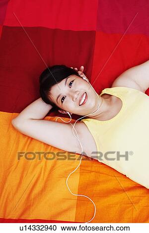 Portrait of a young woman listening to music and lying on the bed View Large Photo Image Stock Image - Portrait of a young woman listening to music and lying on the bed. Fotosearch