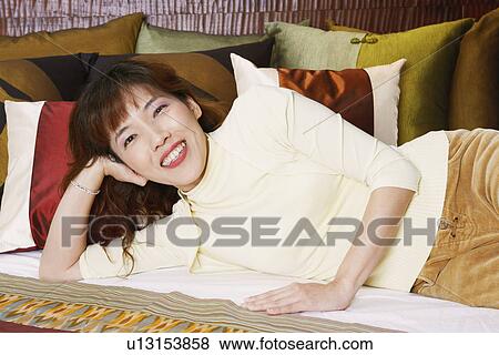 Portrait of a young woman lying on the bed and smiling View Large Photo Image Stock Photo - Portrait of a young woman lying on the bed and smiling. Fotosearch