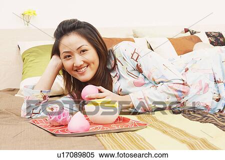 Portrait of a young woman lying on the bed and smiling View Large Photo Image Stock Photography - Portrait of a young woman lying on the bed and smiling. Fotosearch
