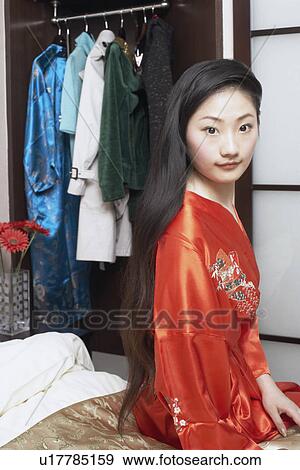 Stock Photo - Portrait of a young woman sitting on the bed. Fotosearch