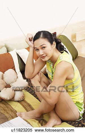 Portrait of a young woman sitting on the bed and smiling View Large Photo Image Stock Photography - Portrait of a young woman sitting on the bed and smiling. Fotosearch