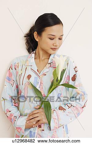 Young woman holding a flower View Large Photo Image Stock Image - Young woman holding a flower. Fotosearch