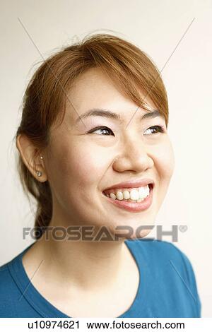 Stock Image - Close-up of a young woman looking cheerful. Fotosearch