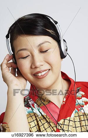 Stock Photograph - Close-up of a young woman wearing headphones and listening to music. Fotosearch