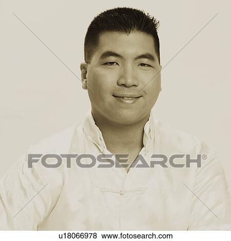 Stock Photo - Portrait of a young man wrapping a gift and smiling. Fotosearch