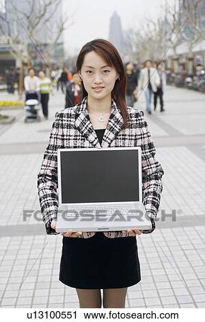 Stock Image - Portrait of a businesswoman holding a laptop. Fotosearch