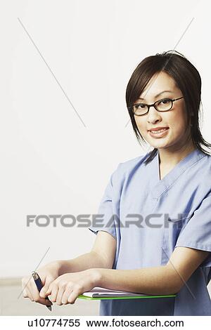 Stock Photography - Portrait of a female doctor holding a clip board and a pen. Fotosearch