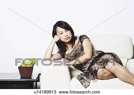 Stock Image - Portrait of a young woman leaning on an armchair. Fotosearch
