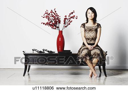 Portrait of a young woman sitting on a table View Large Photo Image Stock Photograph - Portrait of a young woman sitting on a table. Fotosearch