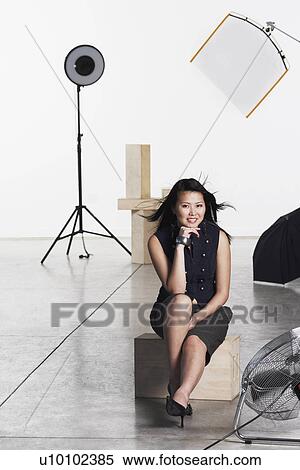 Stock Photography - Portrait of a young woman sitting on a wooden block. Fotosearch