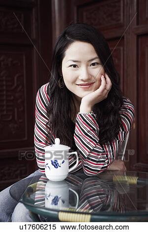 Stock Photography - Portrait of a young woman smiling with her hand under her chin. Fotosearch