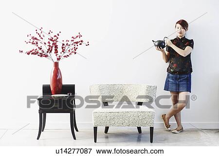 Portrait of a young woman standing with a teapot in her hand View Large Photo Image Stock Photo - Portrait of a young woman standing with a teapot in her hand. Fotosearch