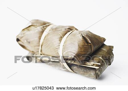 Stock Image - Close-up of rice wrapped in banana leaves. Fotosearch