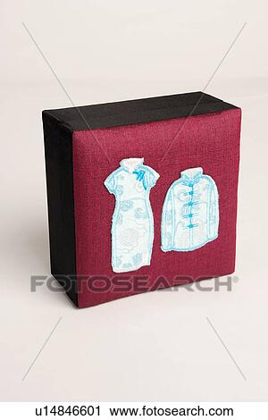 Stock Image - Close-up of traditional Chinese outfits embroidered on a box. Fotosearch