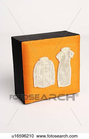 Stock Image - Close-up of traditional Chinese outfits embroidered on a box. Fotosearch
