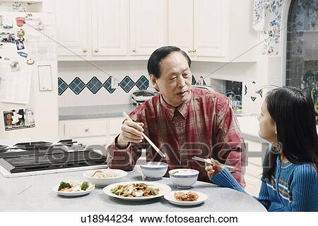 Grandfather and his granddaughter sitting at a table View Large Photo Image Picture - Grandfather and his granddaughter sitting at a table. Fotosearch