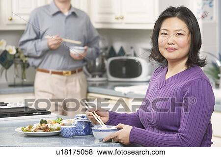 Portrait of a mature woman holding a pair of chopsticks with a senior man standing behind her View Large Photo Image Stock Photo - Portrait of a mature woman holding a pair of chopsticks with a senior man standing behind her. Fotosearch