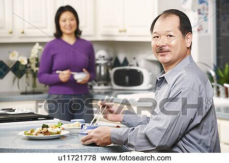 Portrait of a senior man holding a pair of chopsticks with a mature woman standing behind him View Large Photo Image Stock Photo - Portrait of a senior man holding a pair of chopsticks with a mature woman standing behind him. Fotosearch