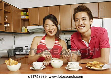 Portrait of a young couple having breakfast at a kitchen counter View Large Photo Image Stock Photo - Portrait of a young couple having breakfast at a kitchen counter. Fotosearch