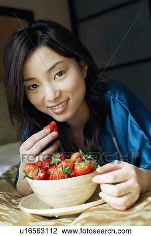 Portrait of a young woman eating a strawberry View Large Photo Image Stock Image - Portrait of a young woman eating a strawberry. Fotosearch