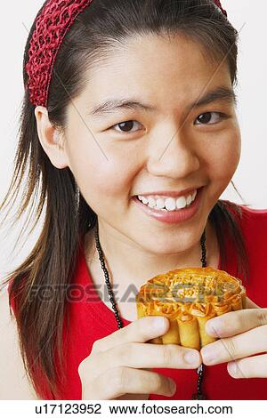 Portrait of a young woman holding a cookie and smiling View Large Photo Image Stock Image - Portrait of a young woman holding a cookie and smiling. Fotosearch